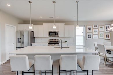 Kitchen with stainless steel appliances, white cabinetry, light wood-style floors, and recessed lighting