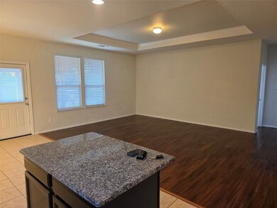 Kitchen with a tray ceiling, dark stone countertops, open floor plan, a center island, and ornamental molding