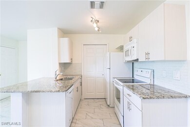 Kitchen with white cabinetry, white appliances, li