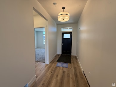Entrance foyer with light wood-style floors and a textured ceiling