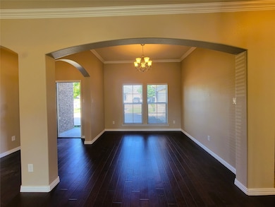 Unfurnished room featuring ornamental molding, a chandelier, arched walkways, and dark wood-style flooring