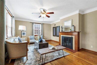 Living room with light wood-type flooring, a tiled fireplace, and ceiling fan