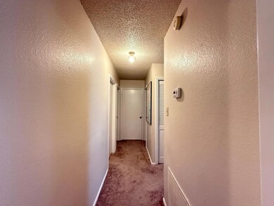 Hallway with carpet flooring, a textured ceiling,