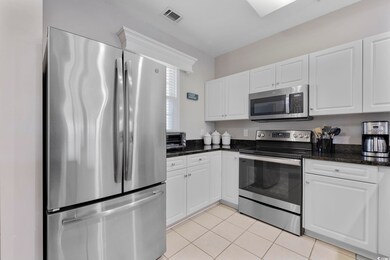Kitchen with visible vents, dark stone counters, a