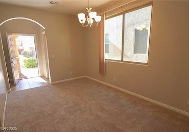 Empty room featuring light carpet and a chandelier