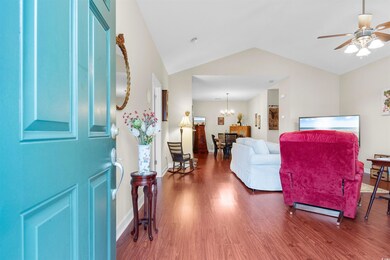 Foyer featuring lofted ceiling, dark hardwood / wood-style floors, and ceiling fan with notable chandelier
