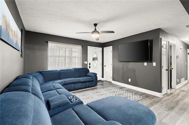 Living area with a textured ceiling, wood finished floors, and a ceiling fan