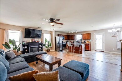 Living room featuring light wood finished floors, a chandelier, and a ceiling fan