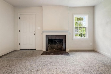 Unfurnished living room with carpet flooring and a tile fireplace