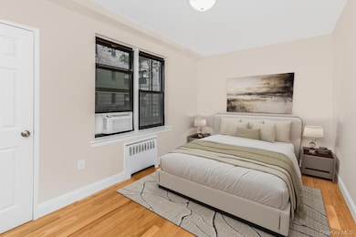 Bedroom featuring radiator heating unit, light wood-style floors, and cooling unit