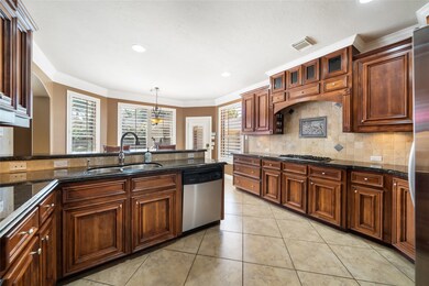Large kitchen with stainless appliances, detailed cabinetry, beautiful backsplash and granite countertops.