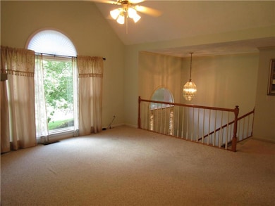 Carpeted empty room with plenty of natural light, a chandelier, vaulted ceiling, and a ceiling fan