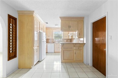 Kitchen with light brown cabinets, white appliances, kitchen peninsula, and light tile patterned floors