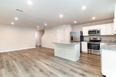 Kitchen with white cabinetry, visible vents, a kit