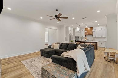 Living room with ceiling fan, light wood-type floo