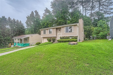 Bi-level home with a chimney, a garage, and a front lawn