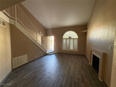 Unfurnished living room featuring a textured wall, a fireplace, dark wood finished floors, and a high ceiling