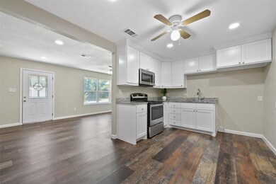 Kitchen with white cabinetry, ceiling fan, dark ha