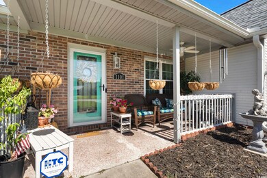 Entrance to property with a shingled roof, brick siding, and ceiling fan