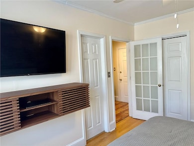Unfurnished bedroom with ornamental molding and light wood-style floors