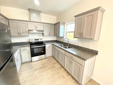 Kitchen featuring dark stone counters, appliances with stainless steel finishes, gray cabinetry, and under cabinet range hood