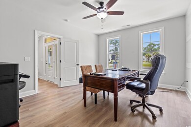 Office area featuring light wood-style floors, a ceiling fan, and baseboards