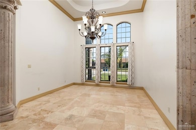 Unfurnished room featuring light tile flooring, decorative columns, a notable chandelier, crown molding, and a raised ceiling