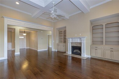 Unfurnished living room with built in features, ornamental molding, beamed ceiling, wood finished floors, and a premium fireplace