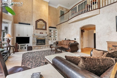 Living area with a stone fireplace, arched walkways, a high ceiling, ornamental molding, and light tile patterned flooring