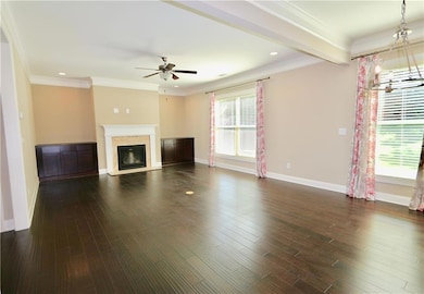 Unfurnished living room with beam ceiling, ceiling fan, dark hardwood / wood-style floors, and crown molding