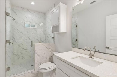 Bathroom featuring vanity, an enclosed shower, and toilet