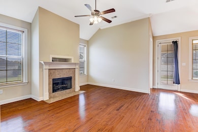 Unfurnished living room with hardwood / wood-style floors, vaulted ceiling, a fireplace, ceiling fan, and ornamental molding