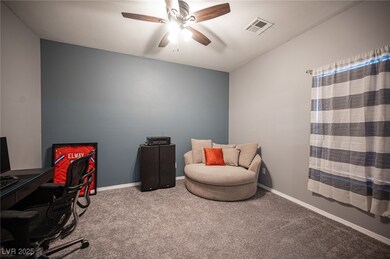 Carpeted office space with a ceiling fan and baseb