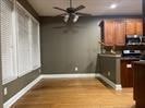 Kitchen featuring baseboards, dark countertops, a ceiling fan, and wood finished floors