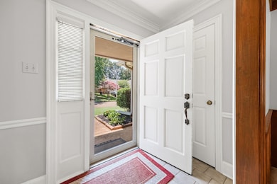Foyer entrance with crown molding and light tile patterned floors