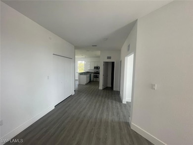 Corridor featuring a sink, baseboards, dark wood f