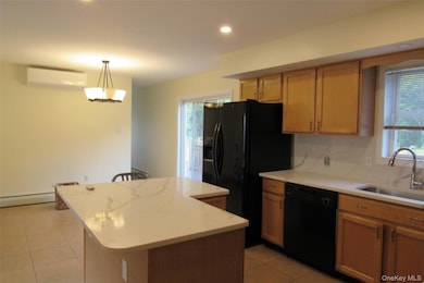 Kitchen featuring a center island, black appliances, recessed lighting, tasteful backsplash, and light tile patterned floors