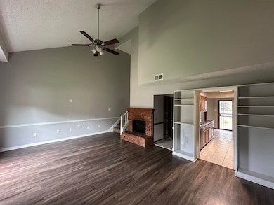 Unfurnished living room with ceiling fan, dark wood-style flooring, high vaulted ceiling, a fireplace, and a textured ceiling