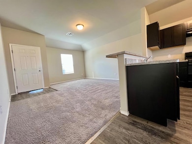 Kitchen featuring black range with electric stovetop, light countertops, open floor plan, dark brown cabinetry, and dark colored carpet