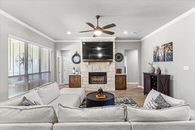 Living room featuring crown molding, a fireplace, wood finished floors, a ceiling fan, and recessed lighting