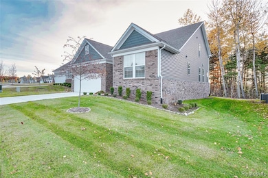 View of front of property featuring a front yard, a garage, concrete driveway, and brick siding