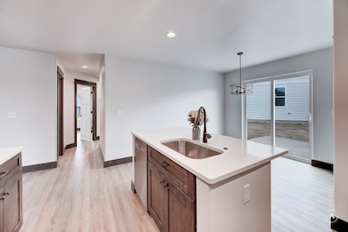 Kitchen with decorative light fixtures, light wood finished floors, recessed lighting, an island with sink, and dishwasher