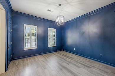 Empty room featuring crown molding, wood finished floors, and a chandelier