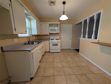 Kitchen featuring white appliances, hanging light fixtures, light tile patterned floors, white cabinetry, and light countertops