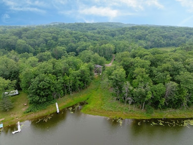 Set on .57 wooded acres along Gardner Lake, it features a pine interior, soaring ceilings, and a wall of windows that bring the outdoors in.