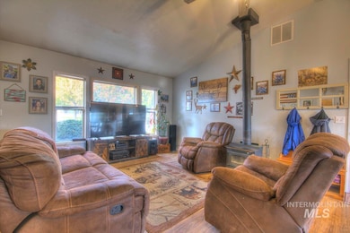 Living room featuring a wood stove, vaulted ceiling, and wood finished floors