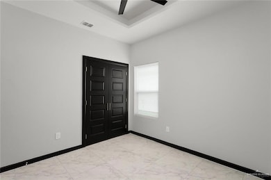 Empty room with light marble finish floors and a tray ceiling