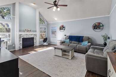 Living area with a textured ceiling, high vaulted ceiling, dark wood-type flooring, ceiling fan, and a tiled fireplace