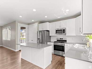 Kitchen featuring appliances with stainless steel finishes, white cabinetry, tasteful backsplash, recessed lighting, and a center island