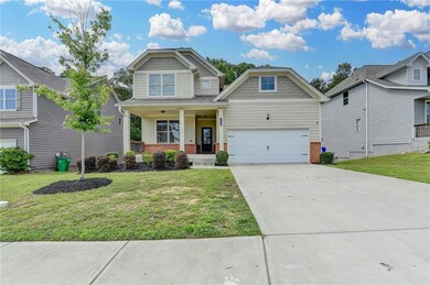 Craftsman-style house with brick siding, covered porch, a front yard, driveway, and a garage